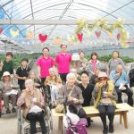 温室内でひな祭りのイベントを楽しむ入居者と職員の交流風景